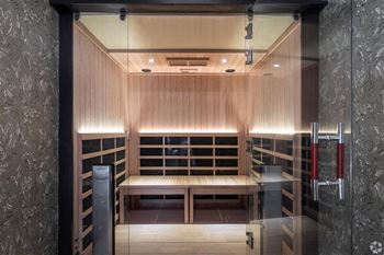 A sauna room with wooden benches and a glass door.